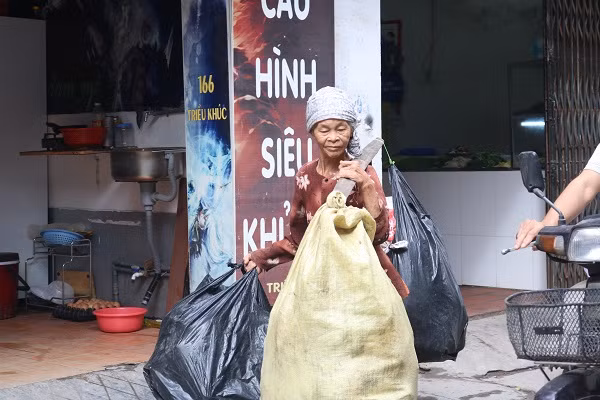 Bà cụ nhặt rác với những túi nilon chất đầy chai nhựa.