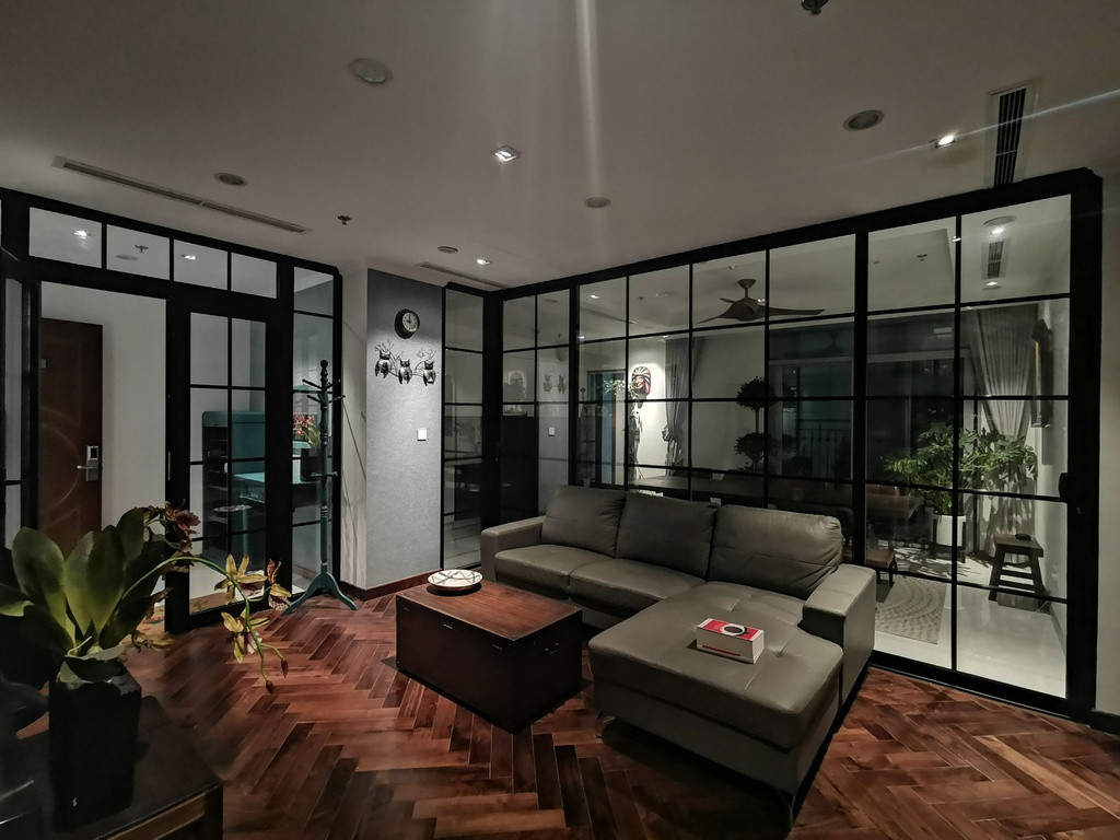 Bên cạch lót gỗ tự nhiên walnut, từ phòng khách còn có thể nhìn ra toàn bộ không gian của căn hộ qua vách ngăn phòng bằng hệ nhôm tạo cảm giác ấm cúng cho các thành viên trong gia đình.