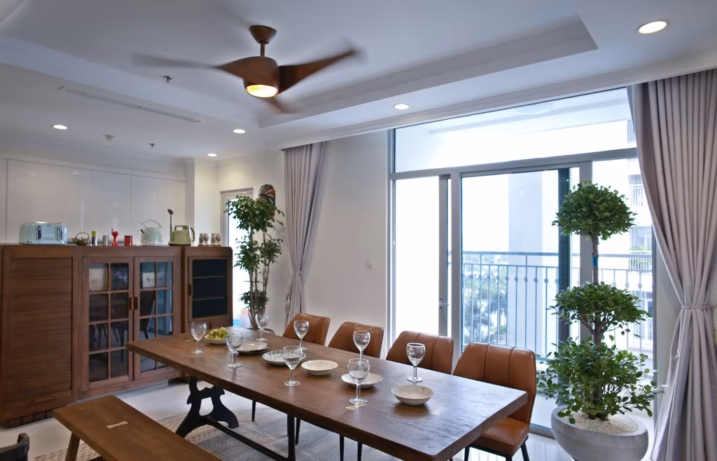 Phòng ăn được ngăn cách với khu bếp bằng kệ tủ cao. Là căn góc của toà nhà nên nhà có đầy nắng và gió, bởi vậy mà những mảng cây xanh được bố trí nhiều hơn.