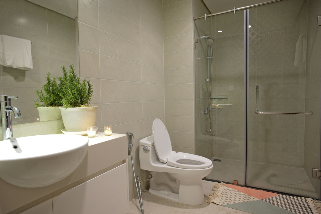 Nhà vệ sinh được thiết kế hiện đại với phòng tắm kính cùng các chi tiết như cây xanh, thảm sàn hoạt tiết cổ điển.