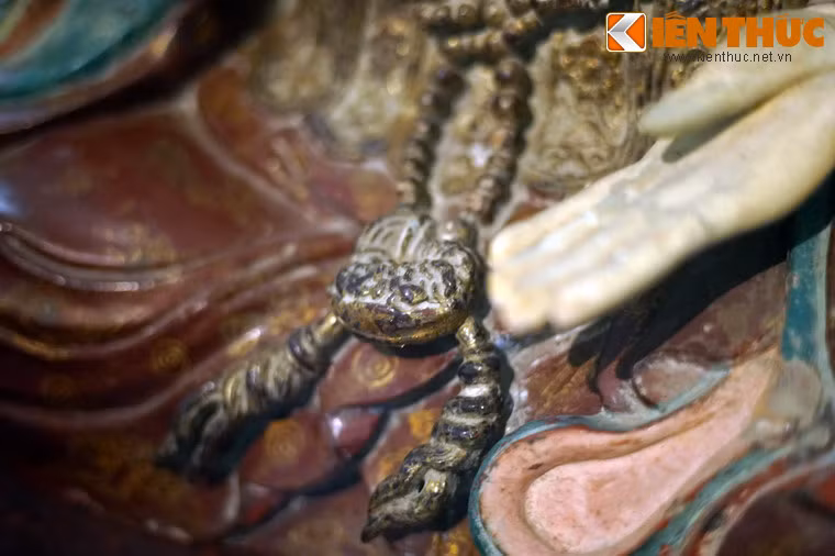 Cổ hoàng hậu đeo chuỗi hạt rủ mềm xuống lòng đùi.