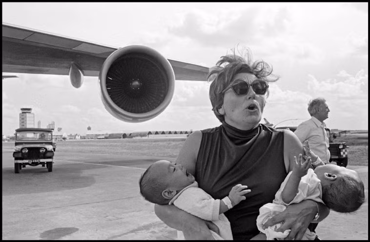 Nhân viên ngoại giao Mỹ đưa trẻ em Việt Nam lên máy bay trong chiến dịch Babylift ở sân bay Tân Sơn Nhất. Ảnh: Hiroji Kubota/ Magnum Photos.