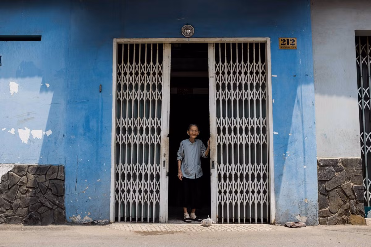 Cụ bà trước cổng nhà ở TP HCM. Ảnh: Mathieu Arnaudet - 500px.com.
