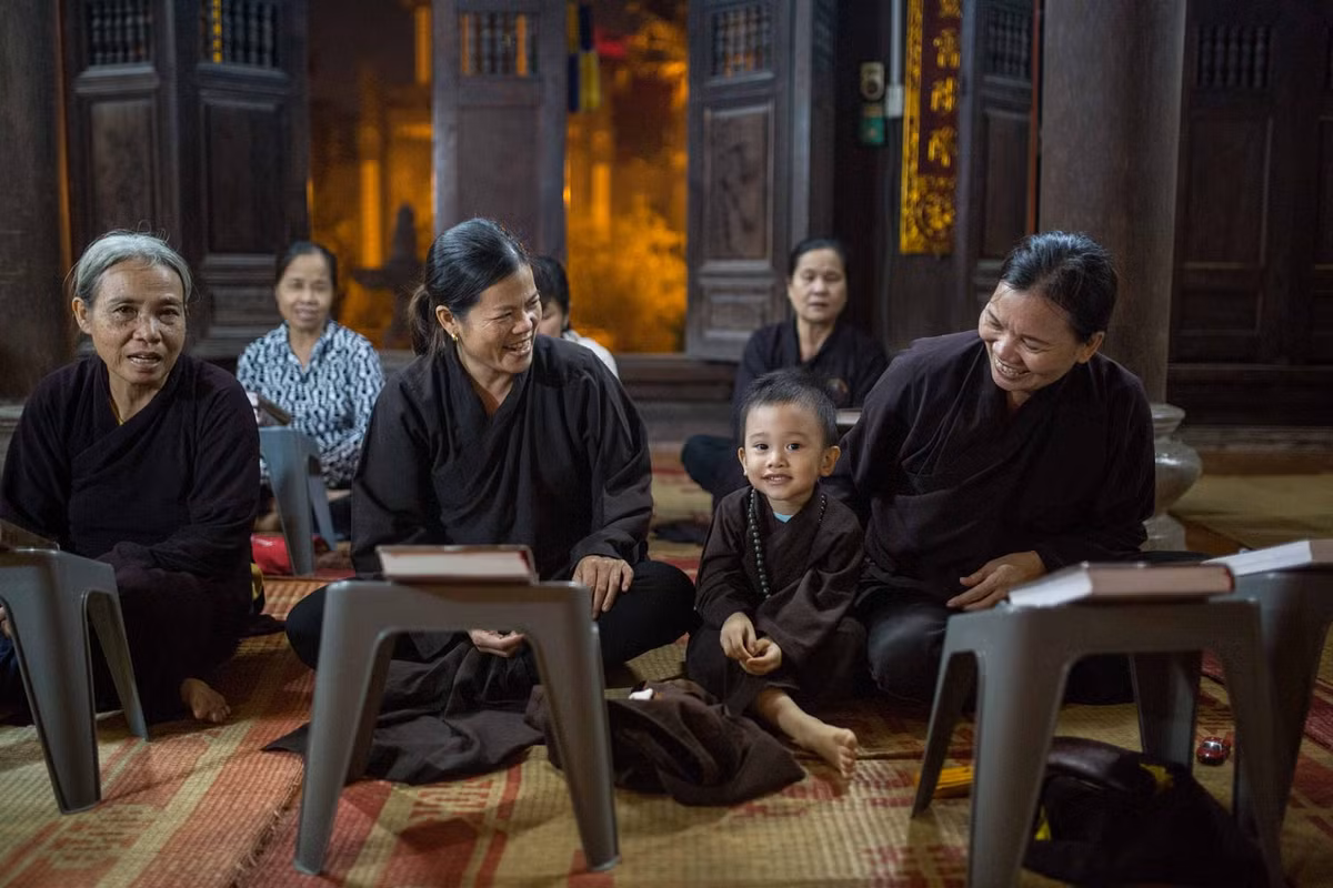 Em bé đi tụng kinh trên chùa cùng bà ở Hà Nội. Ảnh: Mathieu Arnaudet - 500px.com.