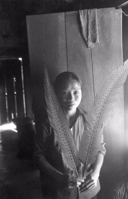 Người phụ nữ khoe hai chiếc lông của con chim trĩ rừng bắt được gần nhà. Ảnh: Ferdinando Scianna/ Magnum Photos.