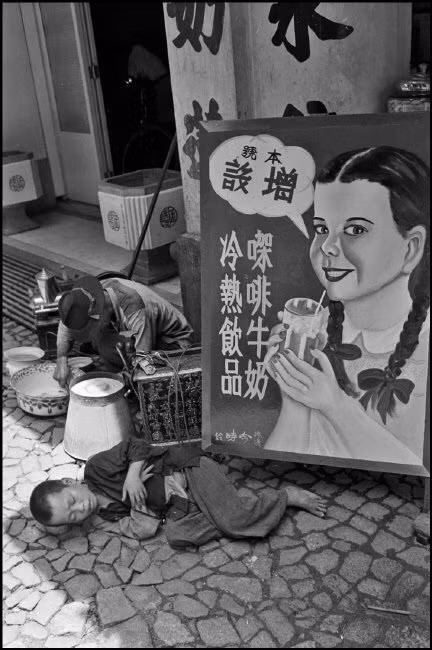 Những người bán hàng rong nghỉ trưa dưới bóng râm của một tòa nhà sang trọng. Ảnh: Werner Bischof/ Magnum Photos.