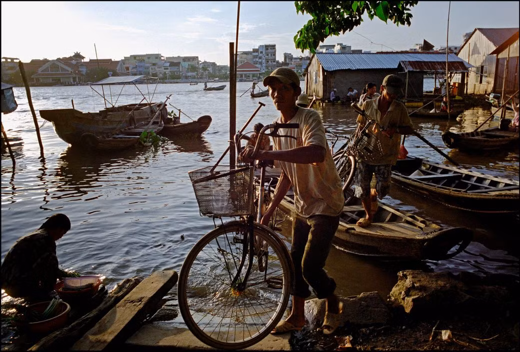 Người dân đưa xe đạp từ đò lên bờ. Ảnh: Ian Berry/ Magnum Photos.