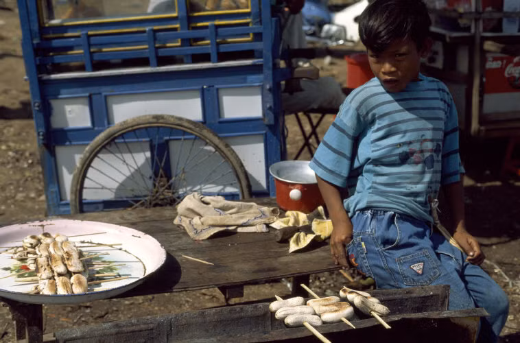 Quầy chuối nướng, món ăn vặt dân dã ở Phnom Penh, 1997. Ảnh: Hiroji Kubota/ Magnum Photos.