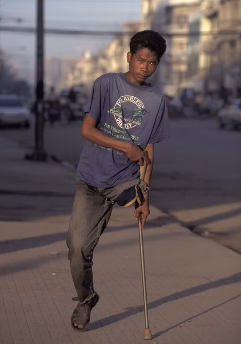 Một người trẻ tuổi bị cụt chân vì bom mìn di chuyển chật vật trên đường phố Phnom Penh năm 1996. Ảnh: Hiroji Kubota/ Magnum Photos.