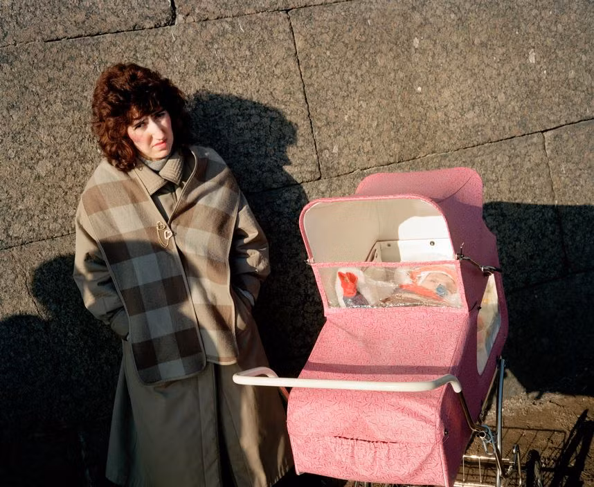 Bà mẹ trẻ cho đứa con sưởi nắng. Ảnh: Martin Parr/ Magnum Photos.