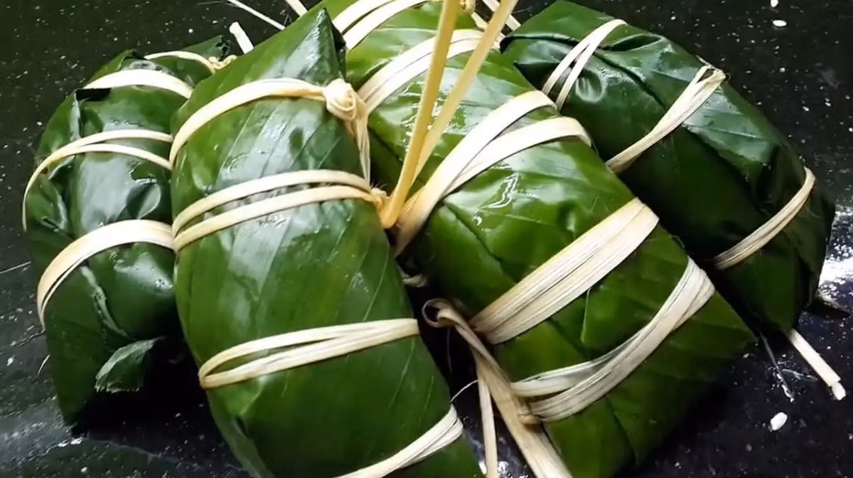 Bánh chưng gù không chỉ là đặc sản Hà Giang nổi tiếng mà còn là biểu tượng văn hoá của người Dao Đỏ. Khác với bánh chưng truyền thống, bánh chưng gù chỉ được gói một lớp lá bên ngoài. Đặc biệt, bánh chưng gù được gói bằng lá dong riềng nên có màu xanh đặc trưng và rất bắt mắt. Ảnh: Traveloka