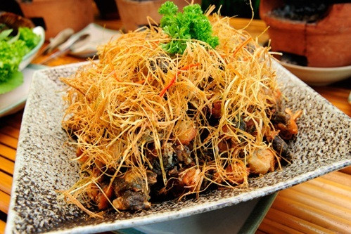 Món ếch núp lùm xuất phát từ món ếch chiên của miền Tây. Sả tươi cắt sợi được cho vào hộp cùng bột chiên giòn xóc đều. “Lùm rơm” chính là sả chiên, bày lên đĩa rồi đặt ếch chiên vào trong.