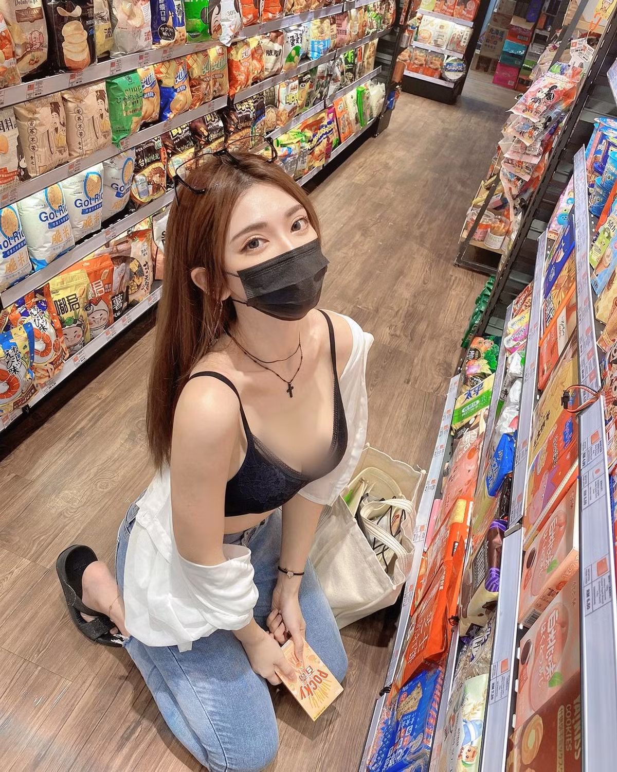 Hot girl này diện quần jeans màu xanh xám, cạp cao, áo crop-top hệt như áo ngực màu đen, khoác ngoài áo sơ mi trắng, đeo khẩu trang, tạo dáng vô cùng gợi cảm.