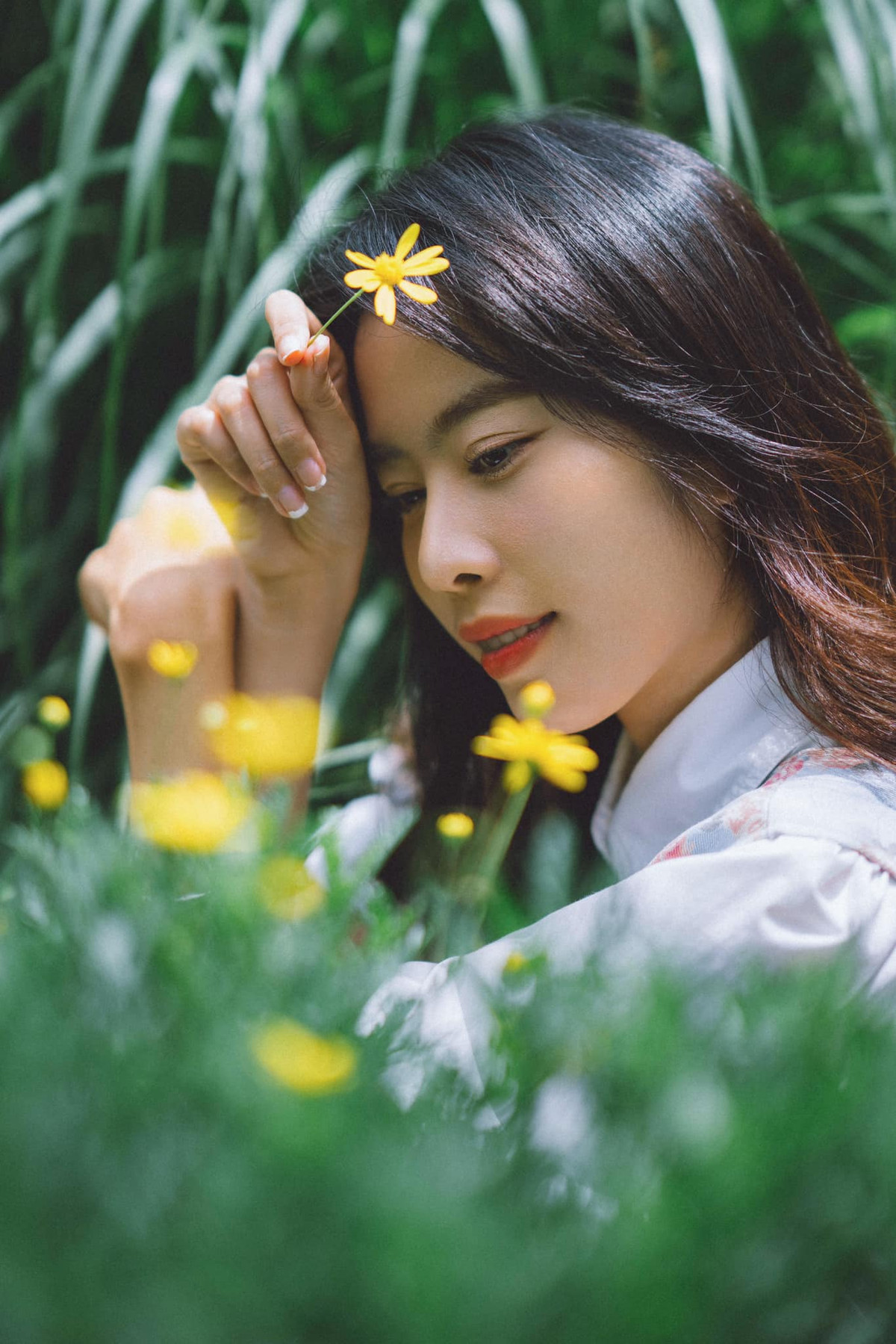 Nam Em diện trang phục dịu dàng, kín đáo kết hợp trang điểm nhẹ nhàng với màu mắt nhạt, môi đỏ cam, uốn tóc xoăn.