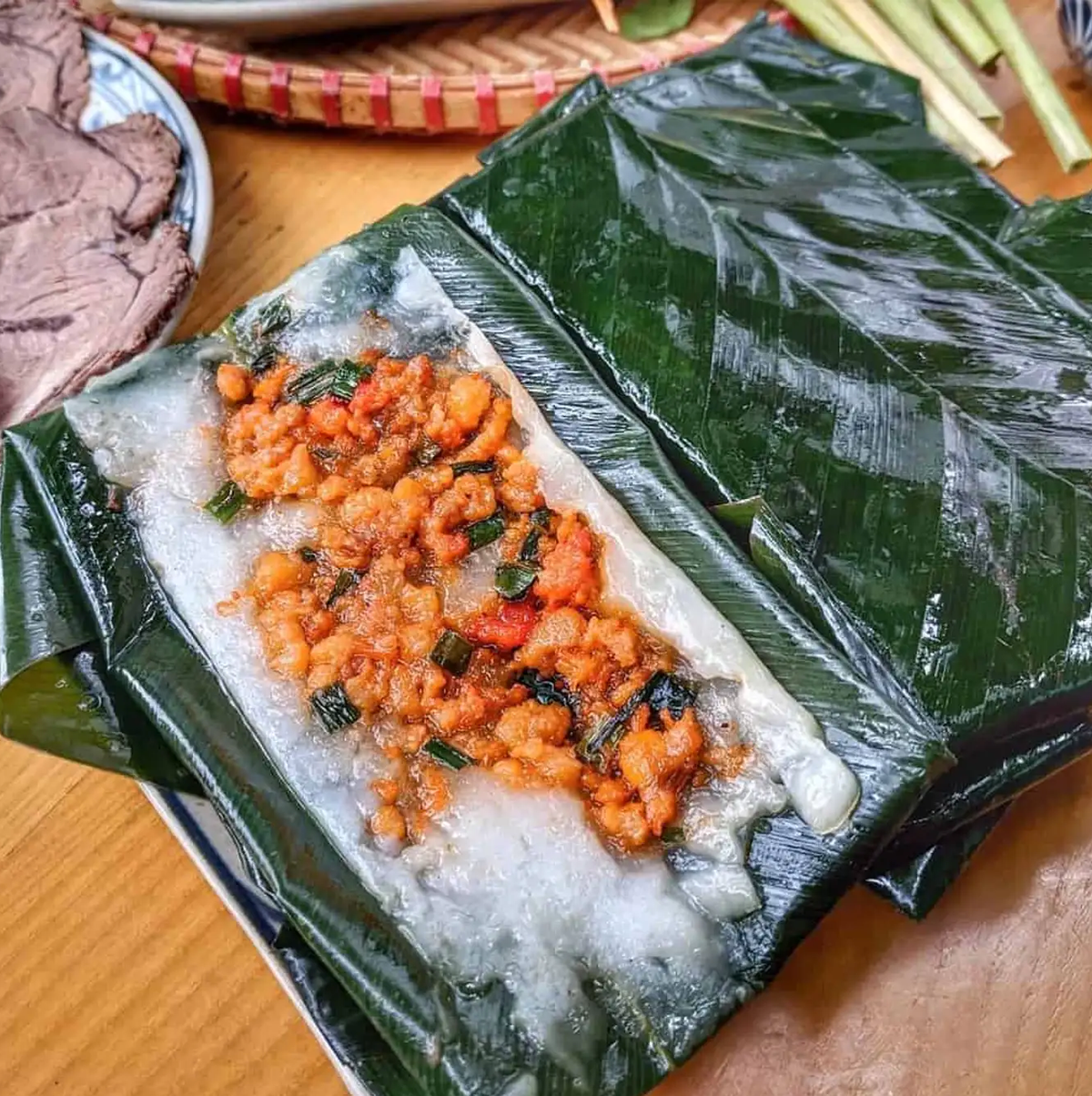 Bánh nậm cũng là một trong những món ăn vặt yêu thích của người dân nơi đây. Chiếc bánh nậm hình chữ nhật, được bọc trong lá dong, với lớp bột trắng ngần điểm xuyến màu tôm hồng bắt mắt. Một bát bánh nậm thường sẽ có thêm chả tôm, chan nước mắm ngọt để làm đậm thêm vị bánh. Ảnh: Traveloka