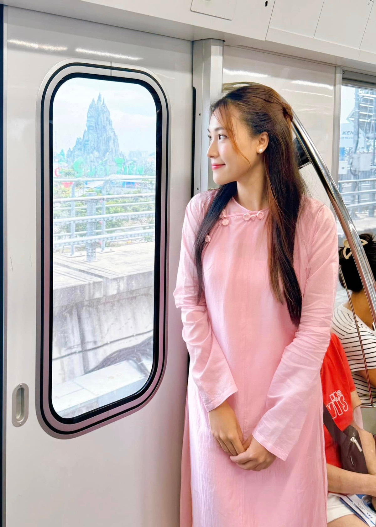 MC Hoàng Oanh mặc áo dài màu hồng, check in trên tàu Metro TP HCM. Ảnh: FB Vu Ngoc Hoang Oanh