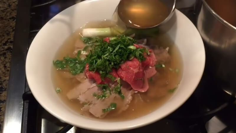 Chan nước dùng nóng hổi vào tô, xếp bánh phở, thịt bò, rau sống lên trên. Thêm một chút tiêu xay và hành lá thái nhỏ. Ảnh: Bách hoá Xanh