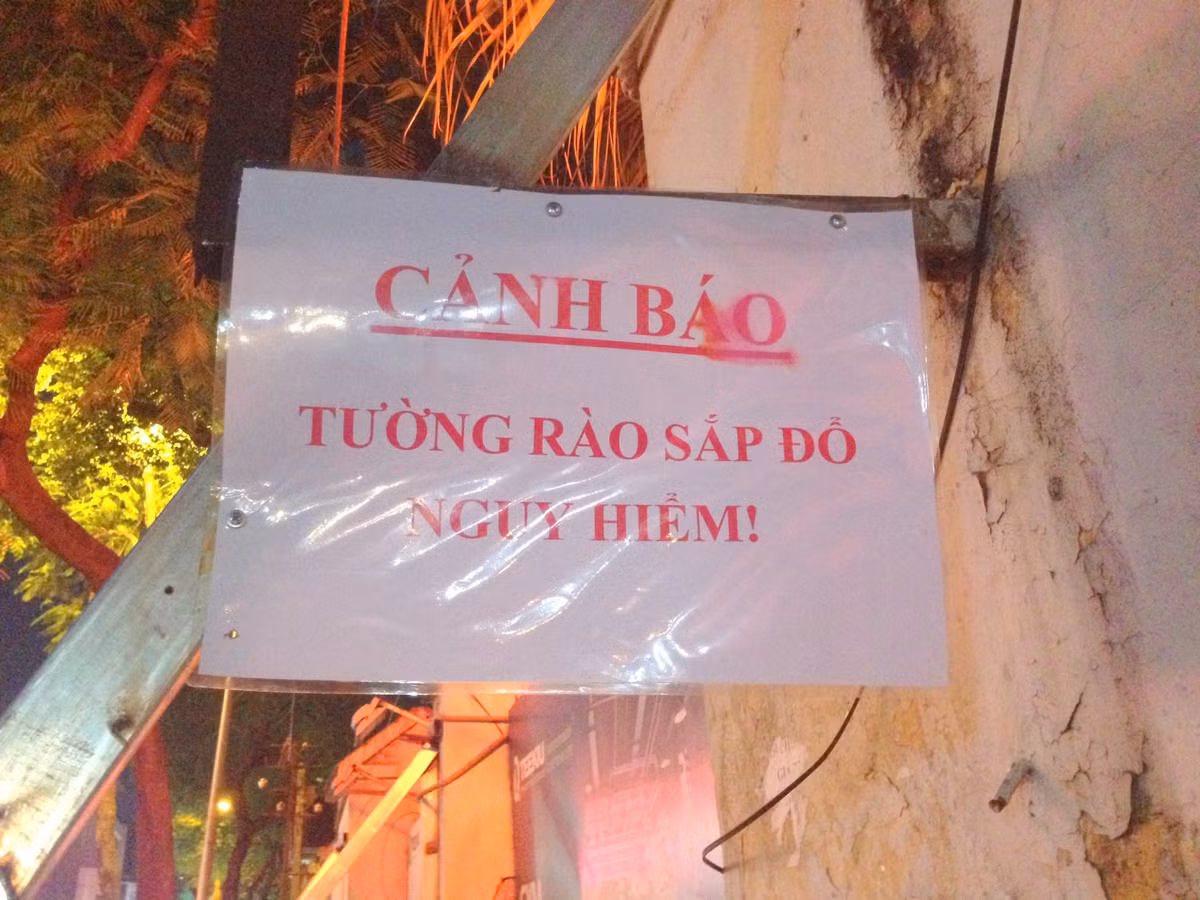 Biển cảnh báo nguy hiểm tường rào sắp đổ được dán hai bên đầu bức tường.