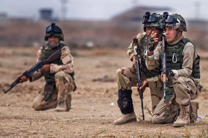 Một tiểu đội trưởng lục quân Iraq bàn cách hiệu quả nhất để tiếp cận một con đường trước hỏa lực đối phương trong một cuộc diễn tập.