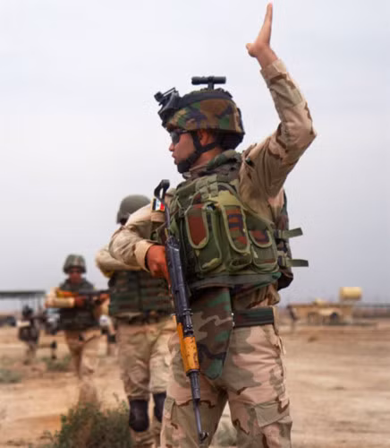 Một quân nhân Iraq ra dấu bằng tay để hướng dẫn các binh sĩ khác phía sau di chuyển vào đúng đội hình.