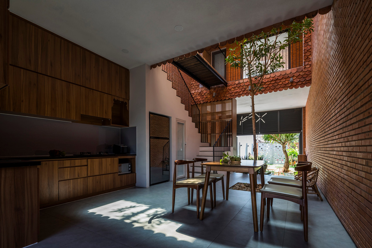 Không gian khách, bếp, các phòng ngủ phân làm hai khối, kết nối nhau bằng hai mái hiên, thông tầng và cây xanh giữa nhà.