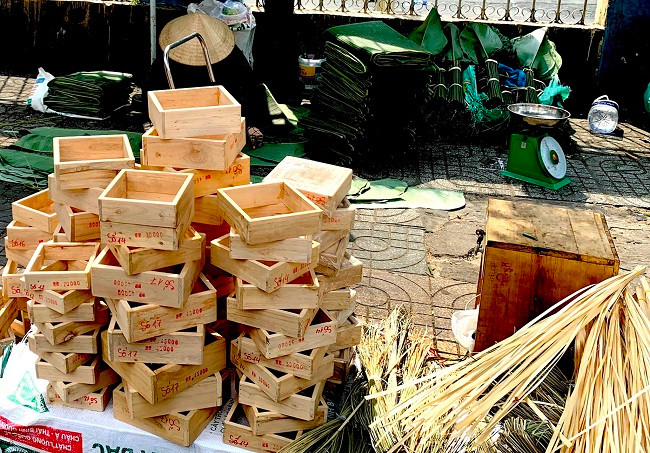 Người bán hàng tranh thủ bày bán các loại lá dong, lá chuối, dây lạt, khuôn bánh chưng và đủ tất cả các vật dụng để có thể gói các loại bánh truyền thống như bánh chưng, bánh tét...Ảnh: Baotintuc