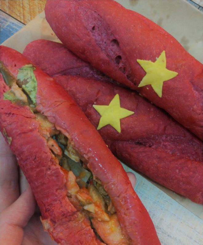 “Bánh mì yêu nước” có vỏ ngoài "giòn rụm”, nhân bánh được đặt bằng những cái tên gợi nhớ về một thời kì đổi mới của đất nước như Pate truyền thống, Tóp mỡ bao cấp, Gà đổi mới, Bò gừng phân phối...Giá bán chỉ 15.000 đồng một chiếc. Ảnh: Hoahoctro
