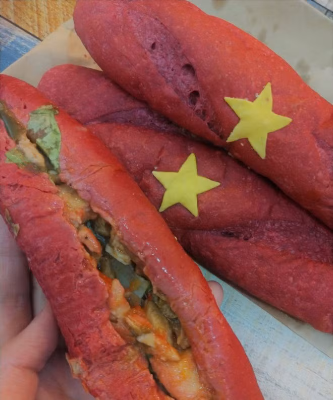 “Bánh mì yêu nước” có vỏ ngoài "giòn rụm”, nhân bánh được đặt bằng những cái tên gợi nhớ về một thời kì đổi mới của đất nước như Pate truyền thống, Tóp mỡ bao cấp, Gà đổi mới, Bò gừng phân phối...Giá bán chỉ 15.000 đồng một chiếc. Ảnh: Hoahoctro