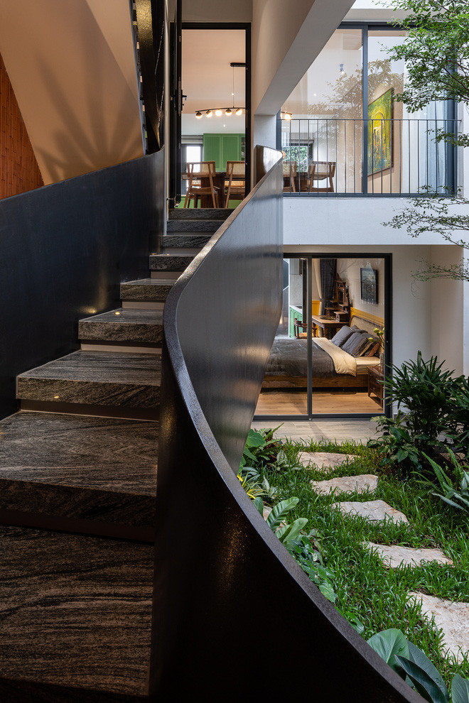 Phía sau phòng khách là khoảng sân rộng thoáng và cầu thang dẫn lên tầng trên.