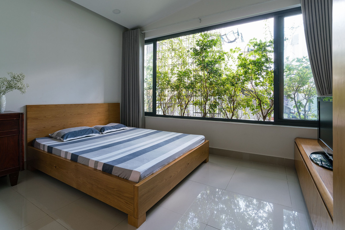 Các phòng ngủ thiết kế đơn giản nhưng thoáng mát nhờ các mảng xanh ở mặt tiền và hông nhà.