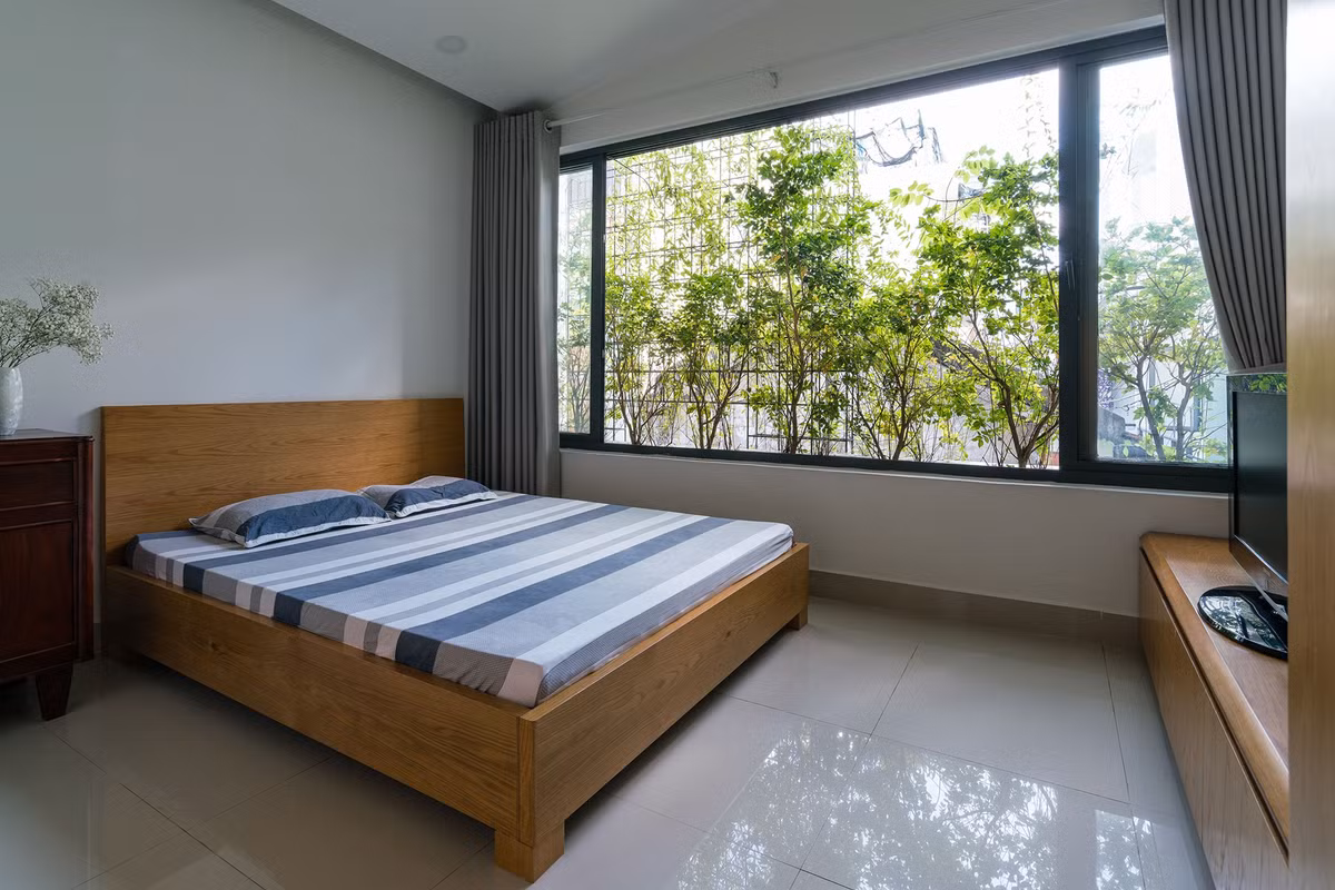 Các phòng ngủ thiết kế đơn giản nhưng thoáng mát nhờ các mảng xanh ở mặt tiền và hông nhà.