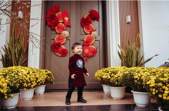 Trước cửa nhà được trang trí bằng những chậu cúc, cành đào và đôi câu đối đỏ.