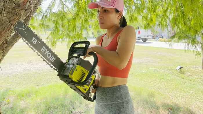 Hồng Ngọc tự tay cầm cưa máy đốn cây trong khu vườn rộng rãi của gia đình.