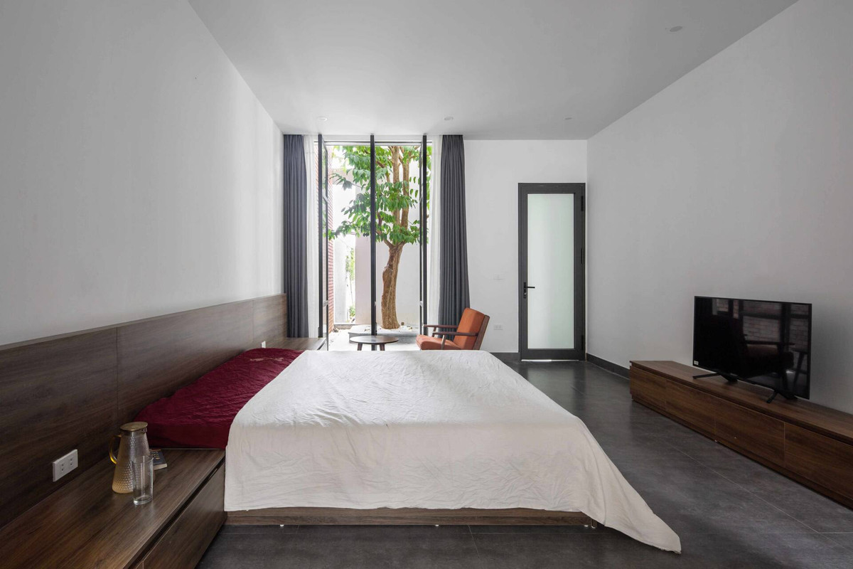 Phòng ngủ chính ở tầng 1 cũng được kết nối ra sân vườn rất thoáng đãng nhờ hệ cửa kính xoay cỡ lớn.