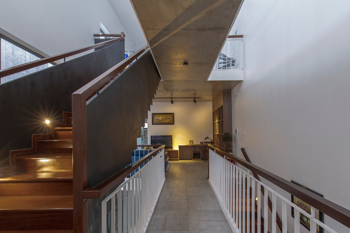 Một hành lang hẹp từ bên ngoài dẫn lối vào bên trong căn nhà, mở ra không gian liên tục dọc theo trục ngang và dọc, được bao quanh bởi các phòng ngủ riêng biệt.