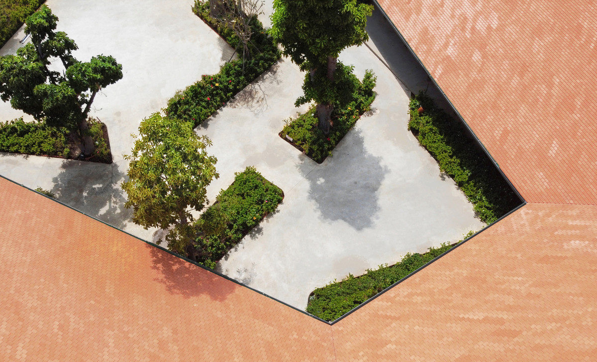 Khoảng sân trong đan xen cây xanh lớn và cây bụi thấp trông bắt mắt với những hình khối thú vị.