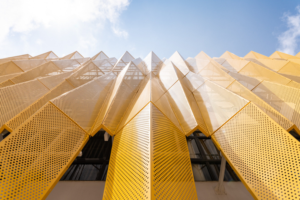 Mặt ngoài là hệ tấm nhôm đục lỗ giảm bức xạ mặt trời và khoảng không gian đệm bên trong như không gian mở của công trình.