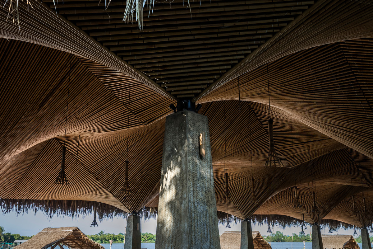 Các trụ cột bê tông nâng đỡ trần tre và mái lá dừa, càng làm tăng tính kết hợp giữa kiến trúc hiện đại và truyền thống.