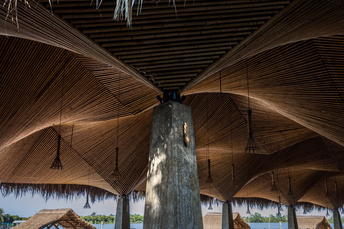 Các trụ cột bê tông nâng đỡ trần tre và mái lá dừa, càng làm tăng tính kết hợp giữa kiến trúc hiện đại và truyền thống.