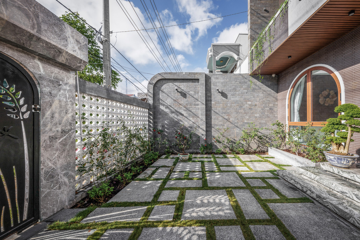 Phần sân trước hiện tại nằm sát đường, khá cao so với vỉa hè và bị cây che lấp. Vì vậy, các kiến trúc sư đã hạ nền đồng thời dỡ bỏ mái che để trả lại sân vườn.