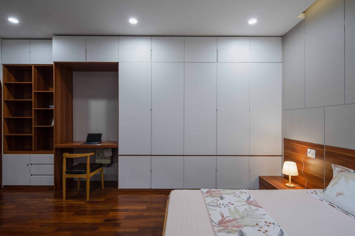 Để tiết kiệm diện tích, kiến trúc sư sử dụng tủ quần áo chạm trần, tích hợp bàn làm việc và kệ lưu trữ đồ.