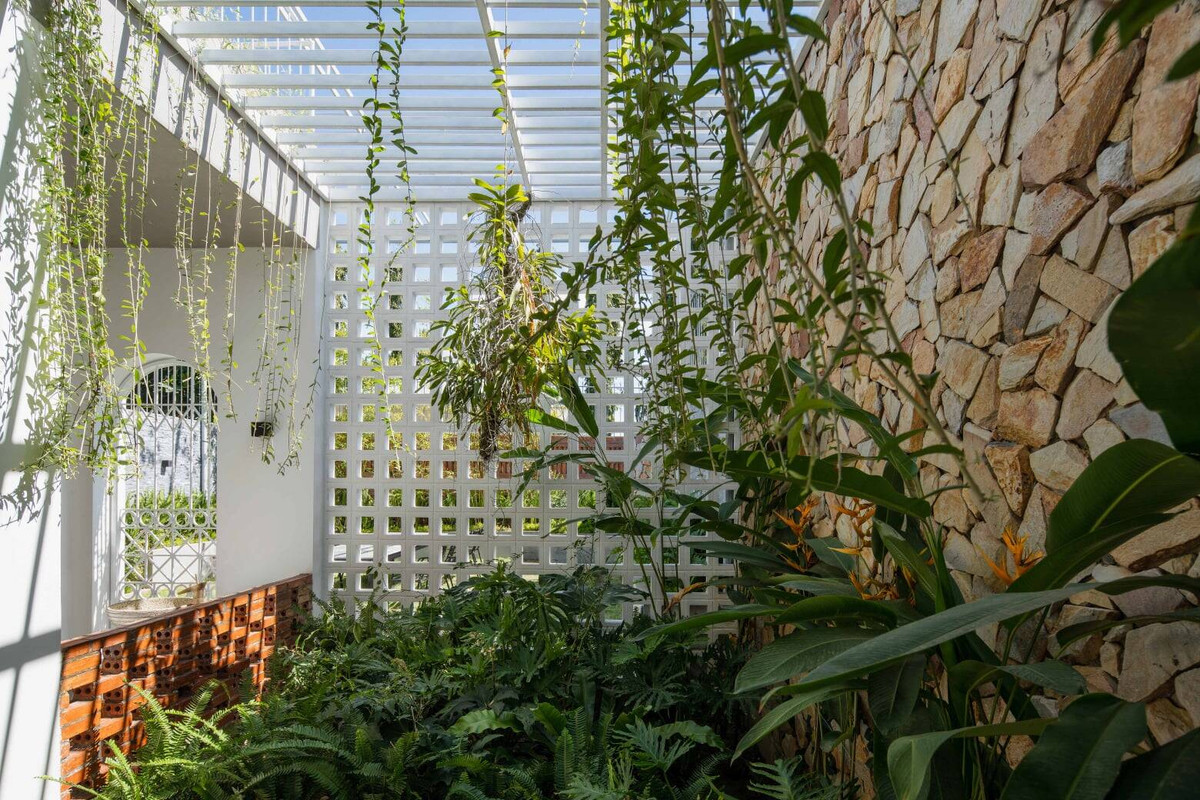 Tường ở khu vực giếng trời được ốp gạch bông gió cùng đá ong vàng tạo nên vẻ tự nhiên.