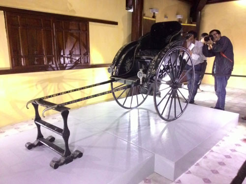 Đây là chiếc xe làm bằng gỗ, dài 230 cm, cao 136 cm và rộng 102 cm, do xưởng Hoàng Hưng ở Hà Nội đóng vào những năm đầu thế kỷ XX. Xe khảm xà cừ trên bản gỗ phủ sơn mài đen, bánh niềng sắt, trên xe gắn 2 đèn lồng. Ảnh: Người lao động.