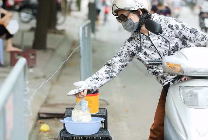 Khách hàng lấy đậu phụ từ chậu rồi bỏ tiền vào xô.Một kiểu kinh doanh độc đáo thời COVID-19. Ảnh: Người lao động