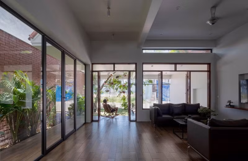 Không gian bên trong nhà được ngăn cách với sân vườn phía trước và phía sau bởi những mảng kính lớn.