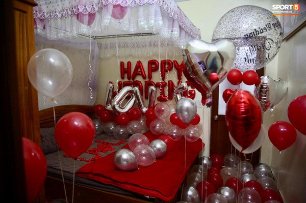 Phòng tân hôn của cặp tân lang - tân nương lấy phông nền đỏ làm chủ đạo với các phụ kiện quen thuộc như bóng bay, hoa hồng xếp tên cô dâu - chú rể.