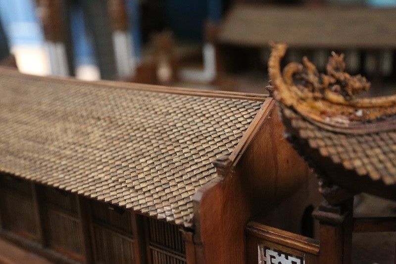 Những viên ngói siêu nhỏ được ông Hùng làm rất tỉ mỉ, từ gỗ ép sơn màu gụ, dập cắt nhỏ thành hình dạng y hệt viên ngói của mái đình rồi đính keo vào nhau. Ảnh: Kinhtedothi.