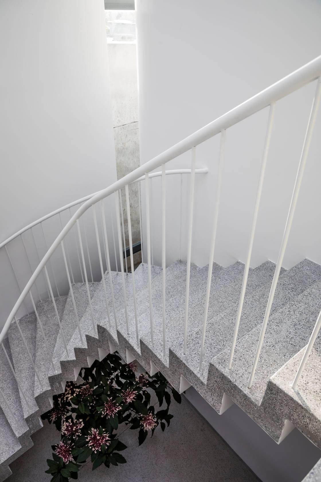 Cầu thang cong kết hợp với khoảng thông tầng ở góc gãy của mảnh đất, tạo cảm giác gọn gàng và phá bỏ góc gãy của công trình.