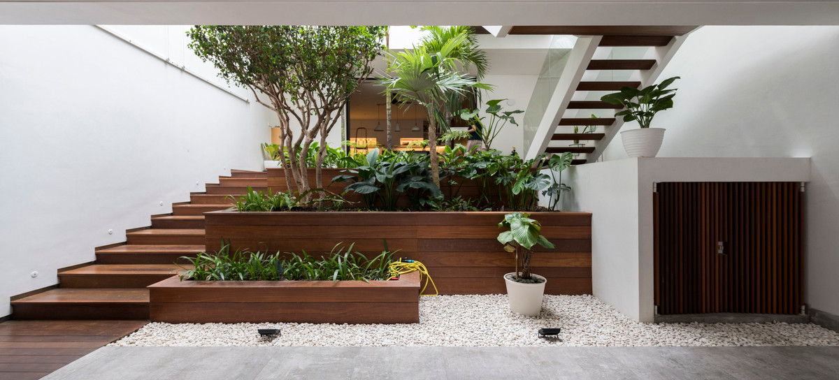 Để giải quyết vấn đề này, kiến trúc sư chia đôi mảnh đất thành hai tòa nhà 3 tầng và 2 tầng. Sân vườn bố trí ở phía trước, trung tâm và phía sau.