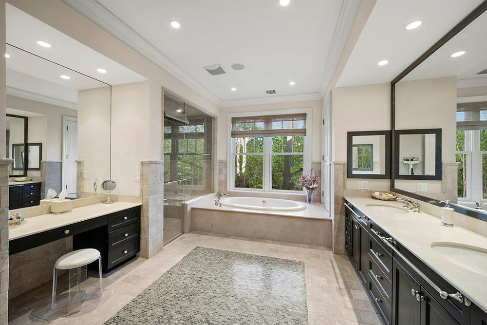 Phòng tắm chính rộng rãi, được lát gạch men màu be, có đầy đủ bồn tắm, vòi sen, và cả bàn trang điểm chuyên dụng.